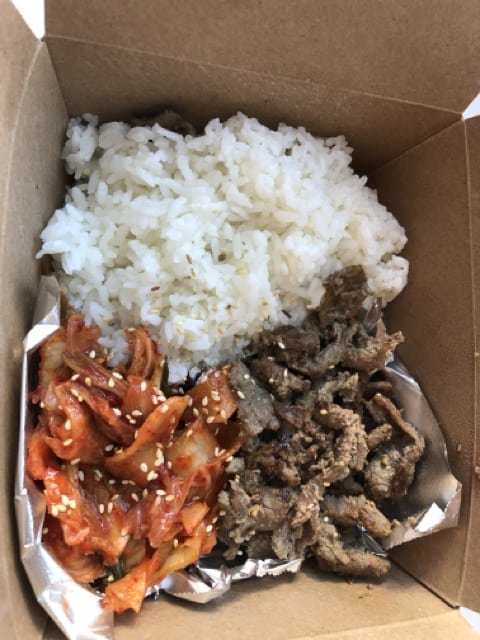 A takeout box of rice, kimchi and Korean beef