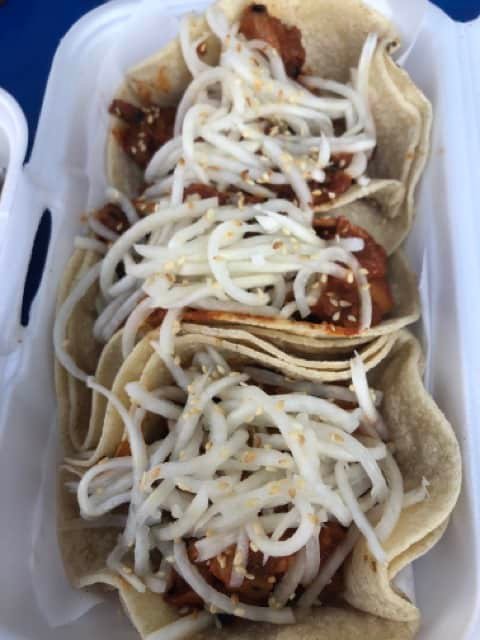 A tray of Korean tacos topped with shredded cheese