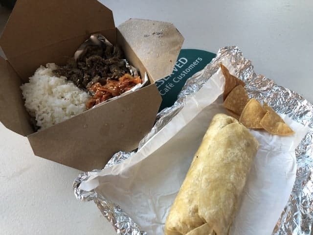 A takeout box of rice and beef next to a burrito wrapped in foil
