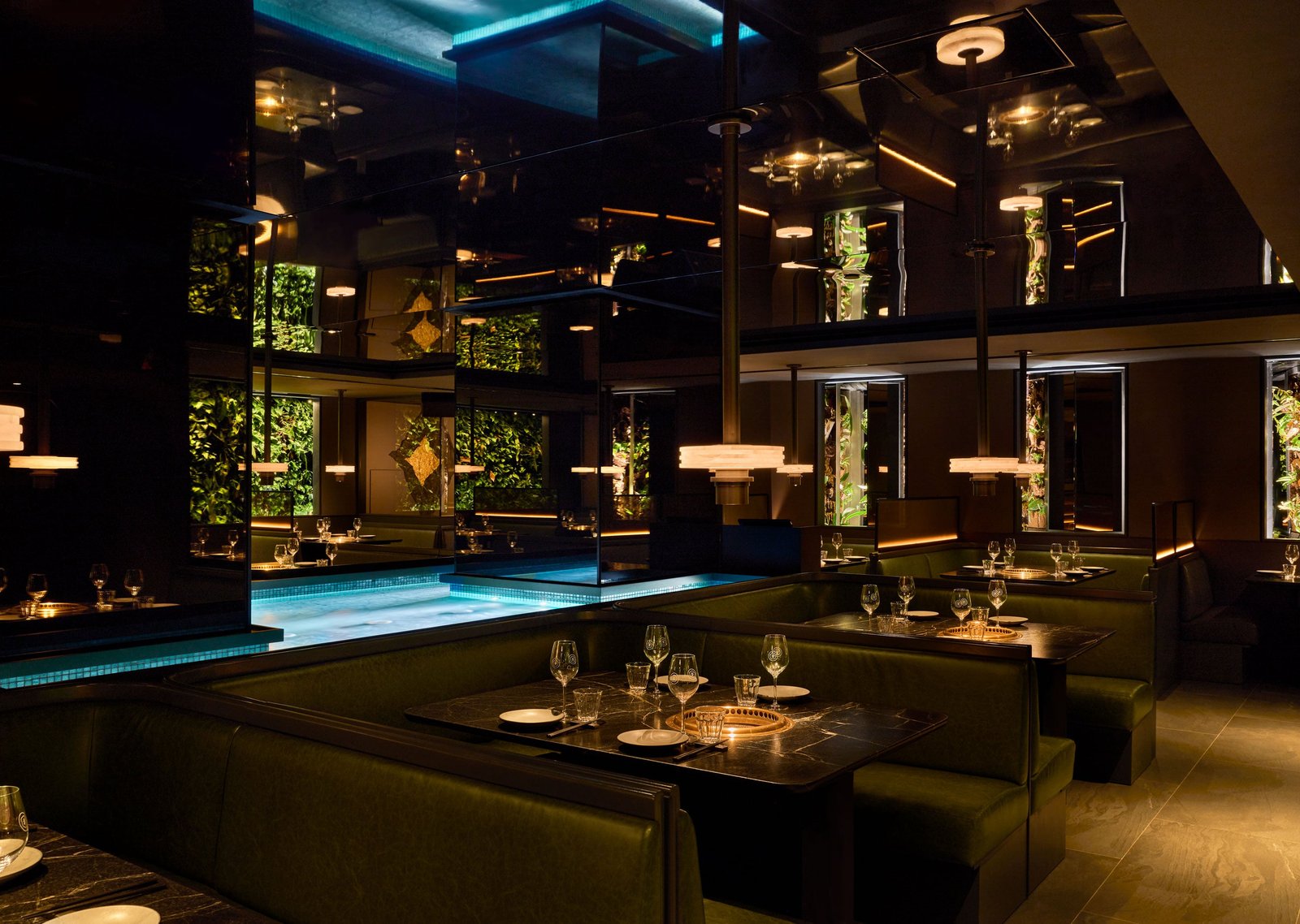 Dimly lit COTE 550 dining room with green leather booths and glowing greenery walls